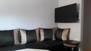 ein Sofa mit Kissen und ein TV an der Wand in der Unterkunft Résidence Mogador in Agadir