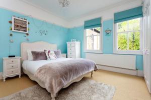 ロンドンにあるVeeve - Vineyard Hill Roadのベッドルーム1室(青い壁と窓のあるベッド1台付)