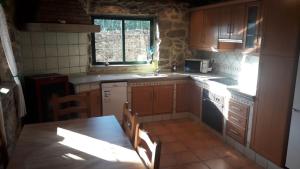 eine Küche mit Holzschränken, einem Tisch und einem Fenster in der Unterkunft Casa Parrilla in Tomiño