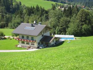 ein Haus auf einem Hügel mit einem großen grünen Feld in der Unterkunft Apartments Spiegl Holzmann in Bischofshofen