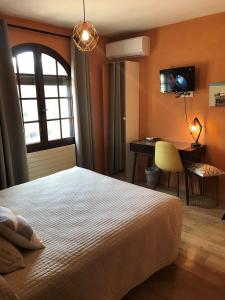 um quarto com uma cama, uma secretária e uma janela em Logis Hôtel Le Manoir & Lounge em Apt