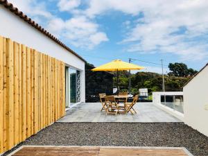 a patio with a table and an umbrella at Casa da Rocha in Terra do Pão