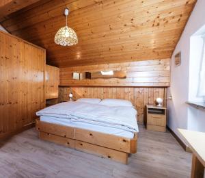 een slaapkamer met een bed in een houten kamer bij Appartamenti Bel Sit in Canazei
