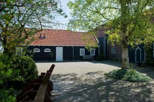a house with a red roof and a tree at Gastenverblijven boerderij Het Driespan in Middelburg