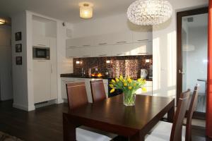 a kitchen with a wooden table with a vase of flowers on it at Apartamenty Adalbert in Gdańsk
