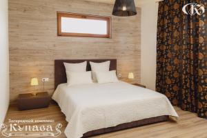 a bedroom with a white bed with a wooden wall at Hotel Complex Kupava in Podvorki