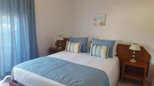 a bed with blue and white sheets and pillows at Mira Parque in Albufeira