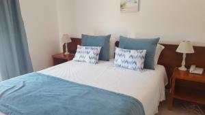 a bedroom with a bed with blue and white pillows at Mira Parque in Albufeira