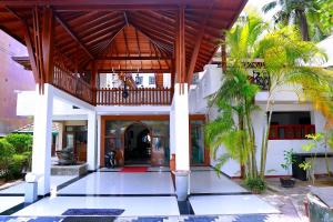 a house with a wooden roof and palm trees at Southern Star Hotel in Bentota