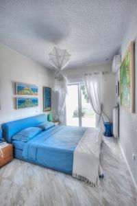 a bedroom with a blue bed and a window at Capo Al Mare villa Sani in Sani Beach