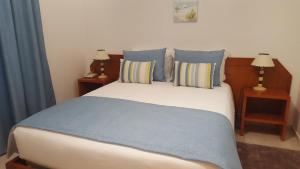 a bedroom with a large bed with blue pillows at Mira Parque in Albufeira