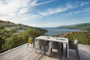 einen Tisch und Stühle auf einem Balkon mit Meerblick in der Unterkunft Apartments Zulijani House Helis B1 & B6 in Rabac