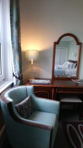 um quarto com uma cadeira e uma secretária com um espelho em 17 Wilmington Square em Eastbourne