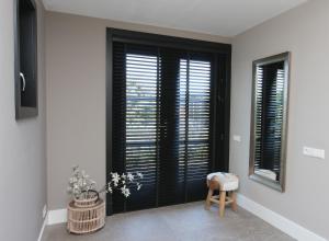 Cette chambre dispose de fenêtres noires avec volets et d'un tabouret. dans l'établissement Chill-out, à Nieuwe Wetering