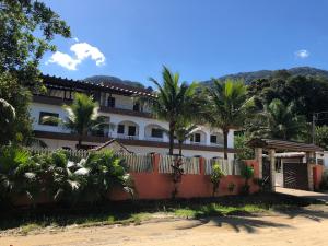 Un edificio con palmeras delante de una valla. en Kitnets Park Verde, en Peruíbe