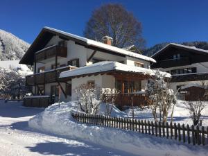 a house covered in snow with a fence at Haus-Schneider-Sepp in Ettal