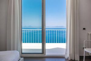een slaapkamer met een glazen schuifdeur naar een balkon bij Villas d'Orlando - with private pool and sea view in Capo dʼOrlando