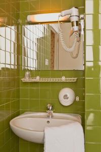 a green tiled bathroom with a sink and a mirror at Hotel Agora in Paris