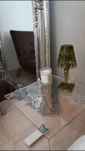 un tavolo di vetro con lampada e specchio di Suite La Damigella a Torri del Benaco