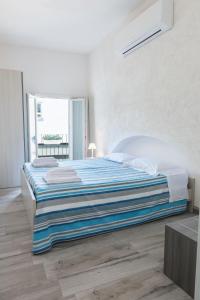 a white bedroom with a bed with a blue blanket at La Dimora sull'Arco in Monopoli