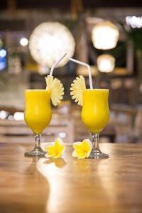 two glasses of orange juice and flowers on a table at Padang Padang Breeze in Uluwatu