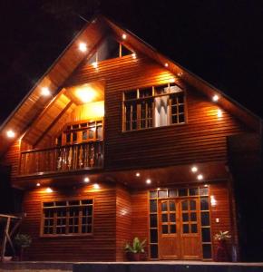 a wooden house with a balcony and a dog in the window at La Cabaña de Noa in Oxapampa