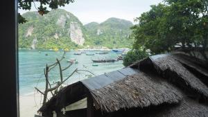 a hut on a beach with boats in the water at Chaokoh Phi Phi Hostel in Phi Phi Islands