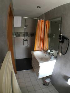 a bathroom with a white sink and a shower at Ambiente Hotel Strehla in Strehla