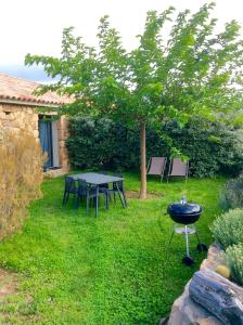 a grill in a yard with a table and a tree at Clos Simoni in Figari