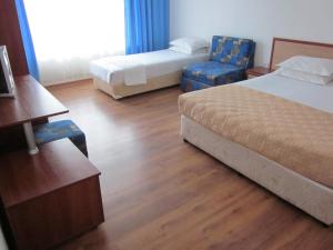 una habitación de hotel con 2 camas y una silla en Albatros 2 Family Hotel, en Kiten