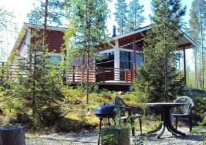 uma casa na floresta com um grelhador e cadeiras em Tiiringolf Cottages em Nilsiä