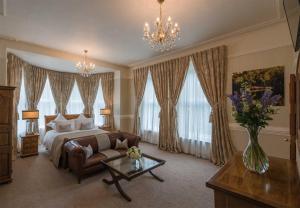 a bedroom with a bed and a couch and a table at Tullyglass House Hotel in Ballymena