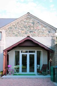 une maison dotée d'une terrasse couverte avec 2 chaises dans l'établissement Hillside Lodge, à Rostrevor
