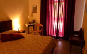 a bedroom with a bed and a window with red curtains at Casale Praia in Letojanni