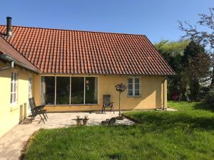 una pequeña casa amarilla con techo rojo en Tranum Lys og Glas en Brovst