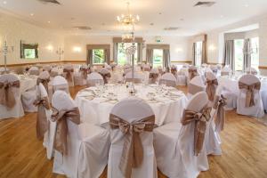 - une salle de banquet avec des tables blanches, des chaises et des bows dans l'établissement Garvock House Hotel, à Dunfermline