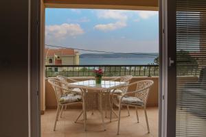a table and chairs on a balcony with a view of the ocean at Apartments Insula in Dobropoljana