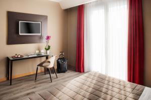 a bedroom with a desk and a bed with red curtains at Hotel Da Vinci in Milan