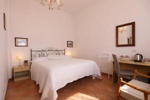 a bedroom with a white bed and a desk and a table and chair at villa oliveta in San Gimignano