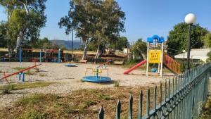 un parque infantil con varios equipos de juego y una valla en Lerna Rooms en Míloi