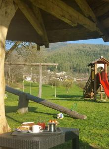 einen Tisch mit einem Teller Essen und einem Spielplatz in der Unterkunft Agriturismo Fattoria Dalcastagnè in Torcegno