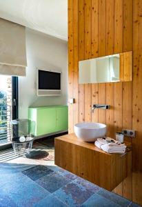 une salle de bain avec une baignoire et une télévision au mur dans l'établissement BB 12 LUBERON chambres d'hôtes contemporaines, à Gordes