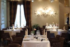 a restaurant with white tables and chairs and a chandelier at MonarC Hotel in Tirana