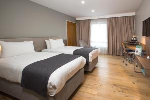 a hotel room with two beds and a desk at Holiday Inn London West, an IHG Hotel in London