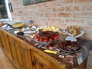 a buffet filled with different types of cakes and desserts at Pousada Casa Pinha em Campos do Jordão in Campos do Jordão