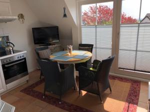 una sala da pranzo con tavolo, sedie e televisione di Kastanienhüs Apartment a Westerland