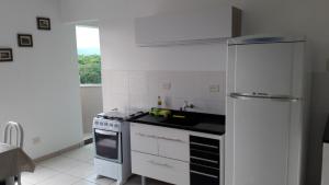 a white kitchen with a stove and a refrigerator at Itanhaém flat residence in Itanhaém