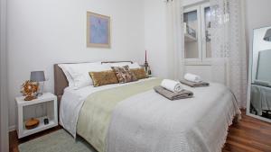a white bedroom with two beds and a window at apartman ami in Split