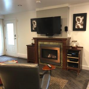 sala de estar con chimenea y TV de pantalla plana en StudioOne Pebble Beach, en Powell River