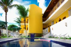 ein gelbes Gebäude mit Palmen und einem Pool in der Unterkunft Pousada Brisa Marine in Conde